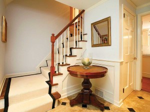 The black tiles in this entry coordinate with the carpeting to provide interest. The round table gives the homeowners a place to set things when they enter.