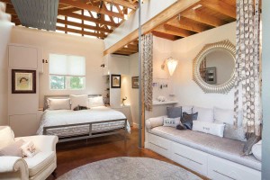 The master bedroom features unique elements like curtains made from wooden slats in front of the alcove.