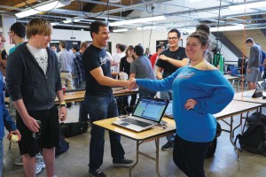 Jose Vietez, co-founder and co-director of Boomtown, shakes hands with up-and-coming programmer Brittany Ann Kos at April’s Hack CU. 
